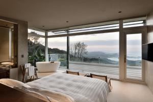 sypialnia z wanną i dużym oknem w obiekcie Daybreak w mieście Jiufen