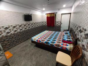 een slaapkamer met een bed en een stoel in een kamer bij Sri Mahalakshmi Deluxe Lodging Arakonam in Arakkonam