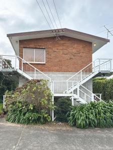 a brick building with a staircase in front of it at Home on The Grange in Mt Eden in Auckland