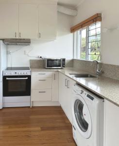 a kitchen with a washing machine and a sink at Home on The Grange in Mt Eden in Auckland