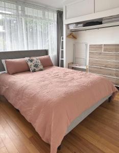 a bedroom with a large bed with a pink blanket at Home on The Grange in Mt Eden in Auckland