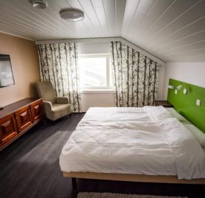 Bed and Breakfast Artjärvi في Artjärvi: غرفة نوم بسرير وكرسي ونافذة