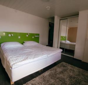 a bedroom with a white bed with a green headboard at Bed and Breakfast Artjärvi in Artjärvi