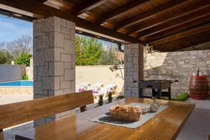 a patio with a wooden table and a fireplace at House Casa Mia 2214 in Orbanići