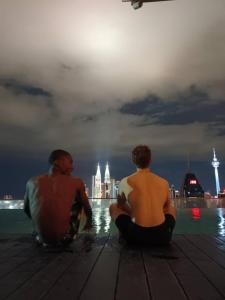 dos hombres sentados en un muelle mirando el agua en Regalia Exclusive Hostel en Kuala Lumpur