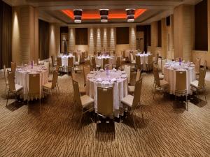 a banquet room with tables and chairs with white tablecloths at The Raintree, Anna Salai in Chennai