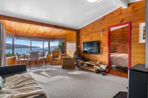 a living room with a bed and a table with a television at Lakeside Lookout - Lake Tarawera Holiday Home in Lake Tarawera
