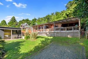 una casa con un gran porche y un patio en Lakeside Lookout - Lake Tarawera Holiday Home, en Lake Tarawera