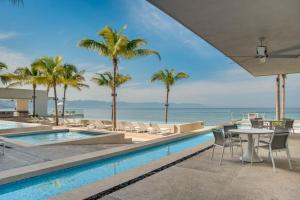 a pool with tables and chairs and palm trees at Harbor 9005 Beachfront 2bdr by Moikkarentals in Puerto Vallarta