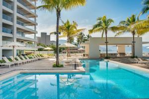 an image of a swimming pool at a resort with palm trees at Harbor 9005 Beachfront 2bdr by Moikkarentals in Puerto Vallarta