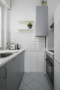 een witte keuken met witte kasten en een wastafel bij Inganni Charme Apartment in Milaan