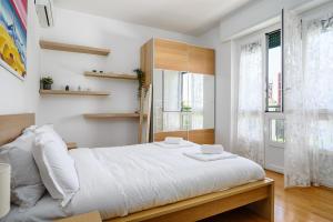 een slaapkamer met een groot wit bed met witte lakens bij Inganni Charme Apartment in Milaan