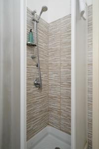 een douche in een badkamer met een houten muur bij Inganni Charme Apartment in Milaan