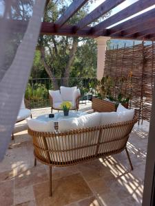 une chaise en osier assise sous une pergola sur une terrasse dans l'établissement Auberge du dom, à Bormes-les-Mimosas