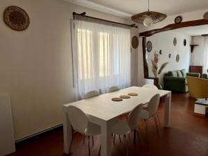 une salle à manger avec une table et des chaises blanches dans l'établissement Appart patio véranda terrasse , à Arbois