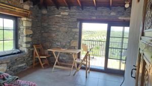 einen Tisch und Stühle in einem Zimmer mit einer Steinmauer in der Unterkunft Peaceful Stone House with Nature View in Karaburun in Izmir