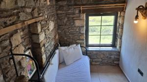1 dormitorio con 1 cama en una pared de piedra en Peaceful Stone House with Nature View in Karaburun, en Izmir