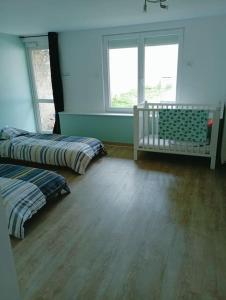 a bedroom with two beds and a baby crib at Chez Isa in Blâmont