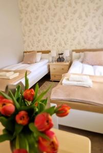 Zimmer mit 2 Betten und einer Vase mit roten Blumen in der Unterkunft Zielono Mi - Dom Gościnny w Łapalicach in Łapalice