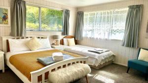 a bedroom with two beds and a chair and windows at Rotorua City Center Holiday House in Rotorua