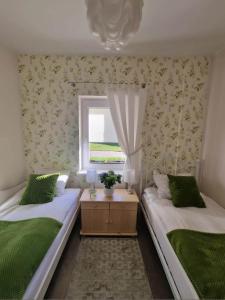 two beds in a room with a window at Zielono Mi - Dom Gościnny w Łapalicach in Łapalice