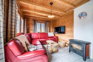 a living room with a red leather couch and a fireplace at Chalet Nid Zut in Châtel
