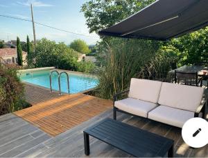 a patio with a white couch and a table and a pool at VillaSarda Drome in Sauzet