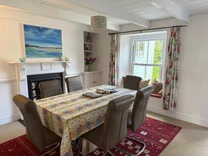 uma sala de jantar com uma mesa e cadeiras e uma lareira em Feock beautiful sunny cottage em Truro