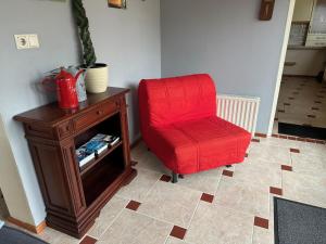 una silla roja sentada junto a un armario de madera en Vakantiehuis het Voorhuis op Landgoed koepeltjesplaats, en Gaast