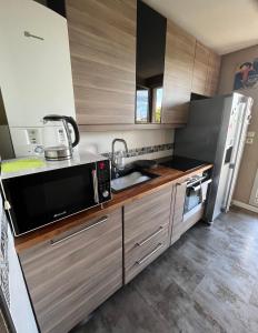 eine Küche mit Holzschränken und einer Mikrowelle in der Unterkunft T2 St Martin du Touch / Airbus in Toulouse