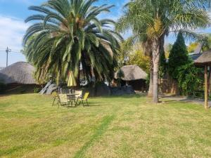a yard with two palm trees and a table and chairs at Luxury Secured Apartment in Centurion