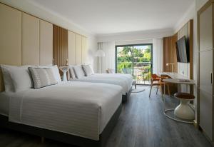a hotel room with two beds and a balcony at Malta Marriott Resort & Spa in St. Julianʼs