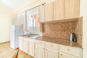 een keuken met witte kasten, een wastafel en een koelkast bij Arianna apartment 14 in Paleokastritsa