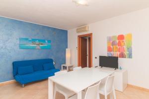 sala de estar con mesa blanca y sofá azul en I Mirti di Porto Pozzo, en Santa Teresa Gallura