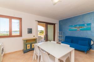 sala de estar con mesa y sofá azul en I Mirti di Porto Pozzo, en Santa Teresa Gallura