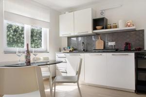 uma cozinha com armários brancos e uma mesa e cadeiras em Appartamento Oliva Villa Arber em Maccagno Inferiore