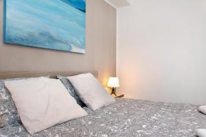 een slaapkamer met een bed met 2 kussens en een schilderij bij Appartamento Oliva Villa Arber in Maccagno Inferiore