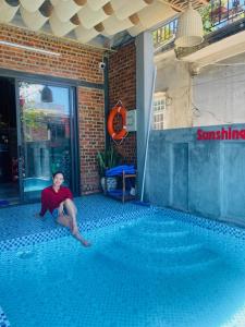 une femme assise à l'étage à côté d'une piscine dans l'établissement Sunshine villa thuan an, à Hue