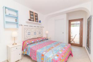 Dormitorio blanco con cama con colcha colorida en Villa Bella, en Santa Teresa Gallura