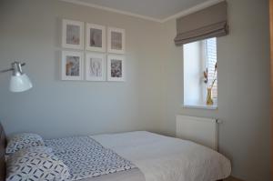 a white bedroom with a bed and a window at Panoramic Apt in the City center in Palanga