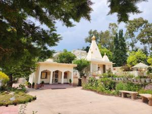 a large white house with a church at Katyuri Kings Divine Homestay- Babaji's cave in Dwārāhāt
