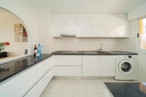 a white kitchen with a sink and a washing machine at Apartment Sandra by the sea in El Campello