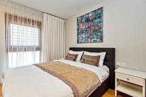 a bedroom with a large bed with a painting on the wall at Gintarinė KOPA in Palanga