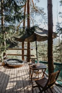 eine Holzterrasse mit einem Tisch und einem Sonnenschirm in der Unterkunft Nature calls - tree tents in Būtingė