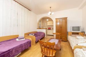 a room with two beds and a table and a tv at Solo Sole apartman 1- Meljine in Meljine