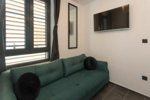 a green couch in a living room with a television at Amaizing apartment near Airport in Kastel Stafilic