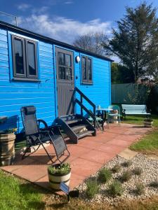 una casita azul con 2 sillas y una mesa en Atlantic Way Shepherd Hut, en Moville
