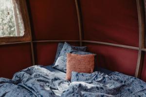 a bed with pillows and a blanket in a room at Nature calls - tree tents in Būtingė
