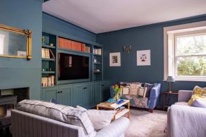 uma sala de estar azul com dois sofás e uma televisão em Hazelhurst em Sway
