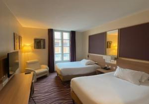 a hotel room with two beds and a television at Plaza Hotel Capitole Toulouse - Anciennement-formerly CROWNE PLAZA in Toulouse